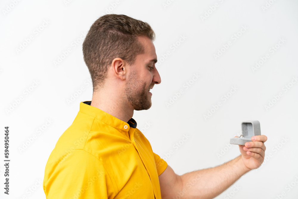 Young man holding a engagement ring isolated on white background with happy expression Young man holding a engagement ring isolated on white background with happy expression