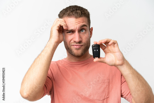 Young caucasian man holding car keys isolated on white background having doubts and with confuse face expression