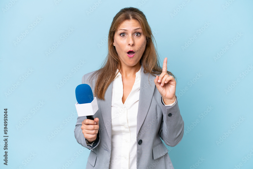 Middle-aged TV presenter woman over isolated blue background intending to realizes the solution while lifting a finger up Middle-aged TV presenter woman over isolated blue background intending to realizes the solution while lifting a finger up