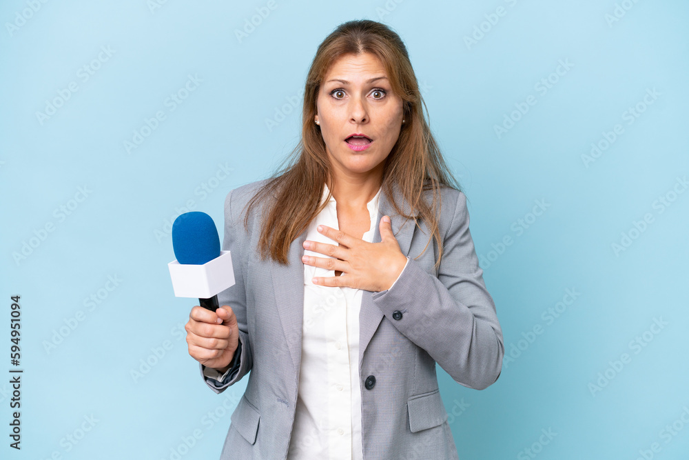 Middle-aged TV presenter woman over isolated blue background surprised and shocked while looking right Middle-aged TV presenter woman over isolated blue background surprised and shocked while looking right