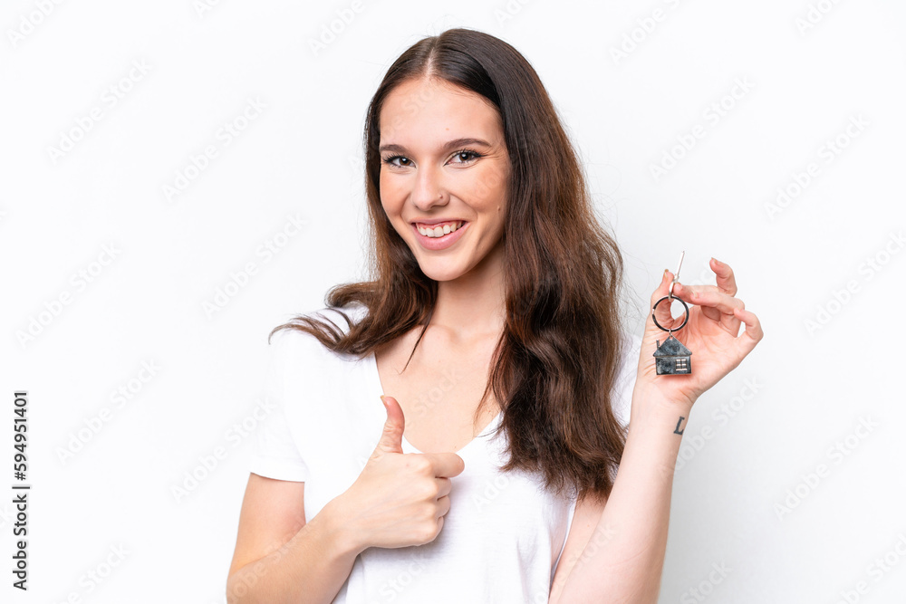 Young caucasian woman holding home keys isolated on white background with thumbs up because something good has happened Young caucasian woman holding home keys isolated on white background with thumbs up because something good has happened
