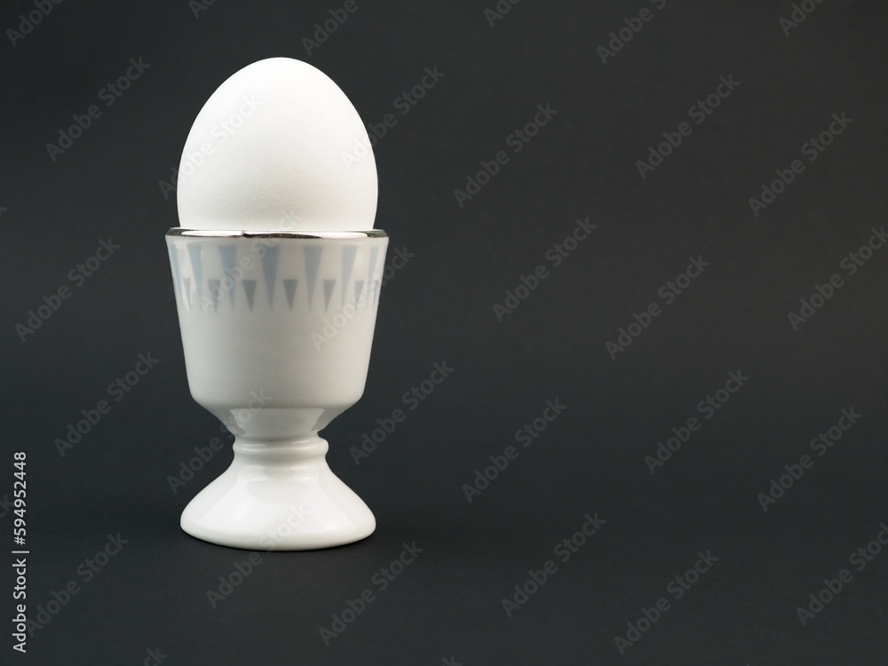 Egg standing on egg cup, isolated on black background Egg standing on egg cup, isolated on black background