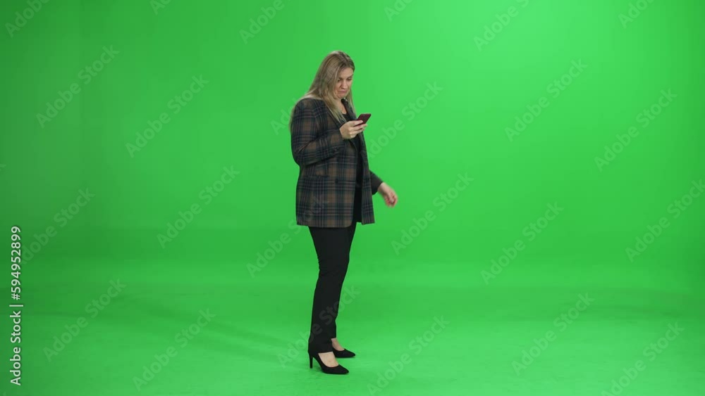Woman uses smartphone on the go, manager on a green background, communicates online, chromakey template, side view. Woman uses smartphone on the go, manager on a green background, communicates online, chromakey template, side view.