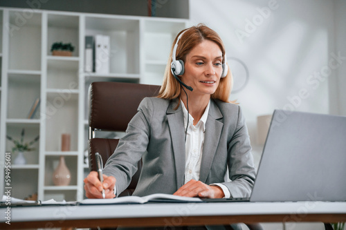 Writing information into document. Woman in business formal clothes is working in office