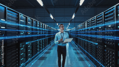 Fotografia Futuristic 3D Concept: Big Data Center Chief Technology Officer Using Laptop Standing In Warehouse, Information Digitalization Lines Streaming Through Servers