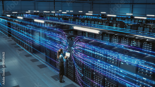 3D Graphics Concept: Big Data Center Female Chief Technology Officer Using Laptop Standing In Warehouse, Activates Servers, Information Digitalization Starts. SAAS, Cloud Computing, Web Service