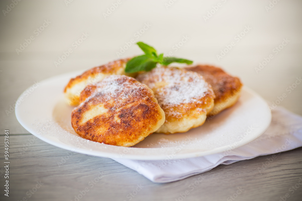 Sweet cooked cheesecakes in powdered sugar in a plate Sweet cooked cheesecakes in powdered sugar in a plate