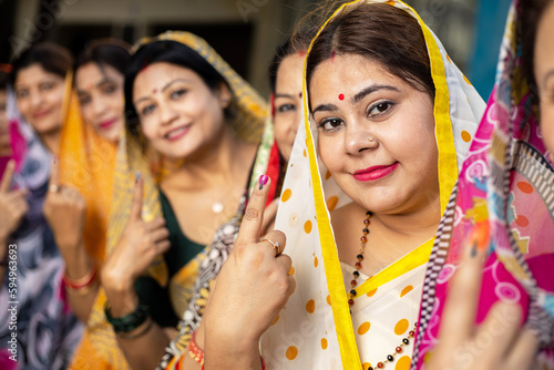 Φωτογραφία Group of happy traditional indian women standing in queue showing their finger marked with black ink after casting vote