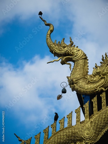 Low angle of Golden Dragon Naga ornament on Buddhist Temple in Thailand © Joshua P Jacks/Wirestock Creators
