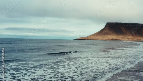 Waves on black beach in front of beautiful Icelandic coastline