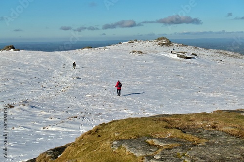Hiker walking on the mountain covered by snow in Dartmoor National Park, UK