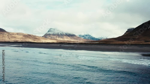 Waves on black beach in front of beautiful Icelandic coastline