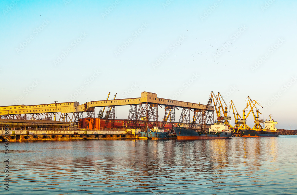 A dry cargo ship and a tanker ship are standing at the port of Constanta Romania and are being loaded.