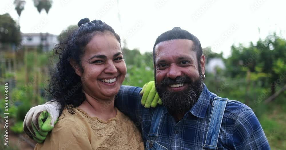 Indian couple smiling in front of camera from garden outdoor - Asian family having fun cultivating healthy food - Vegetarian and family concept Indian couple smiling in front of camera from garden outdoor - Asian family having fun cultivating healthy food - Vegetarian and family concept