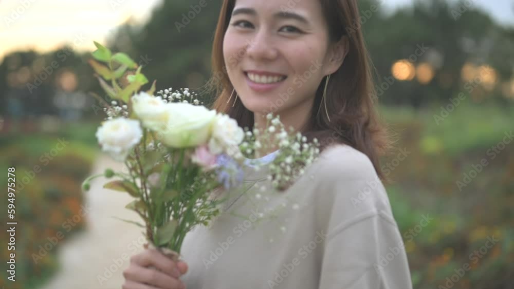 夕方の公園で花束を持って微笑む女性 夕方の公園で花束を持って微笑む女性