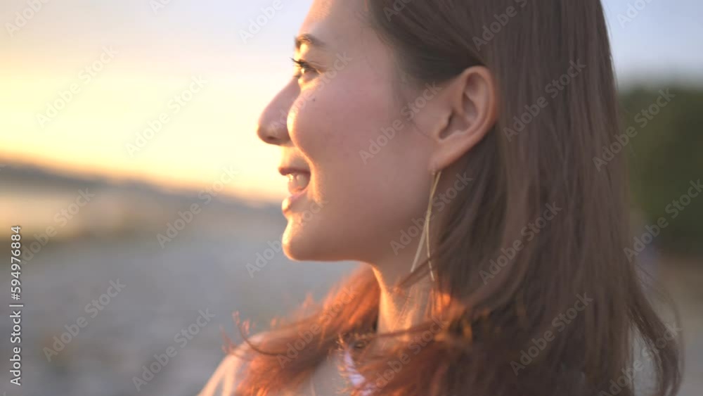 川辺で夕焼けの空を眺める女性の横顔アップ 川辺で夕焼けの空を眺める女性の横顔アップ