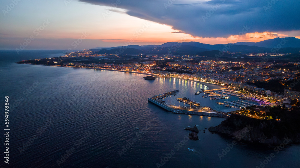 Obraz premium Blanes city port in Barcelona, Costa Brava. Convent de Santa Anna. Mediterranean sea. Yachts and boats. Night aerial view with lights. Drone footage.