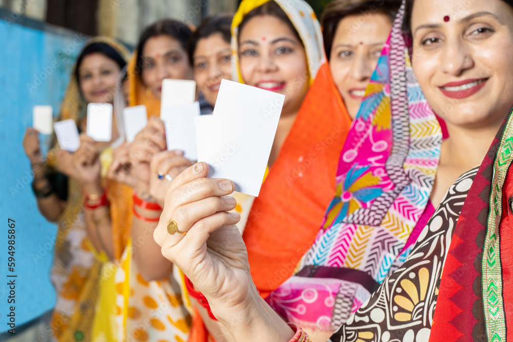 Obraz premium Group of happy traditional indian women wearing sari standing in queue showing blank id card. Mockup.