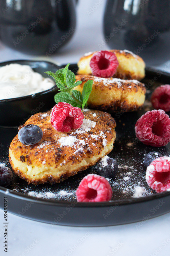 Delicious cheesecakes with berries and sour cream. Delicious breakfast. Morning Delicious cheesecakes with berries and sour cream. Delicious breakfast. Morning