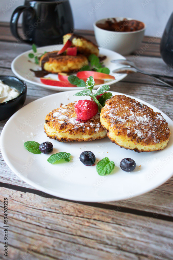 Delicious cheesecakes with berries and sour cream. Delicious breakfast. Morning Delicious cheesecakes with berries and sour cream. Delicious breakfast. Morning