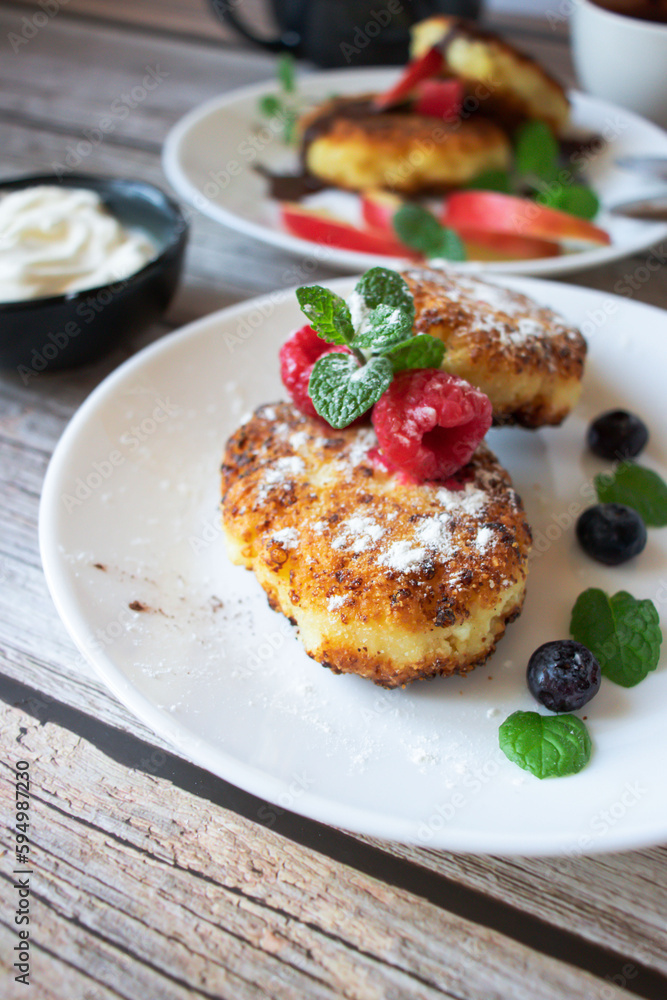 Delicious cheesecakes with berries and sour cream. Delicious breakfast. Morning Delicious cheesecakes with berries and sour cream. Delicious breakfast. Morning