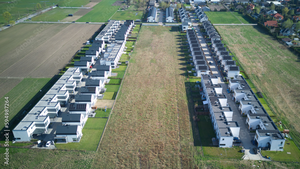 Aerial spring view of warm sunny neighbourhood community houses with single street and field around. Aerial spring view of warm sunny neighbourhood community houses with single street and field around.