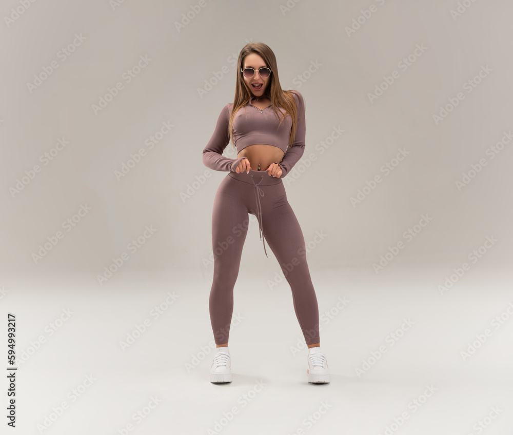 sexy athletic girl in a tight fitness tracksuit on a light background copy paste in the studio