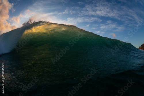 dark and moody wave breaking close up with blue sky background