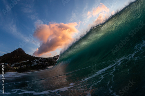 huge wave crashing on the beach at sunset