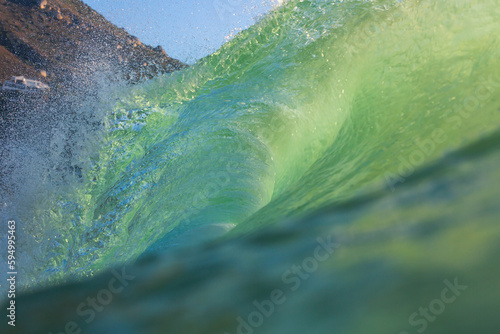 green wave crashing on a beach close up