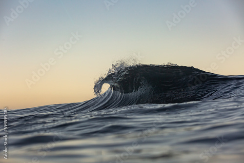 perfect wave breaking at sunrise with golden light © Ryan