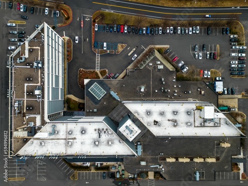 Aerial top view of a large building and a parking lot full of vehicles