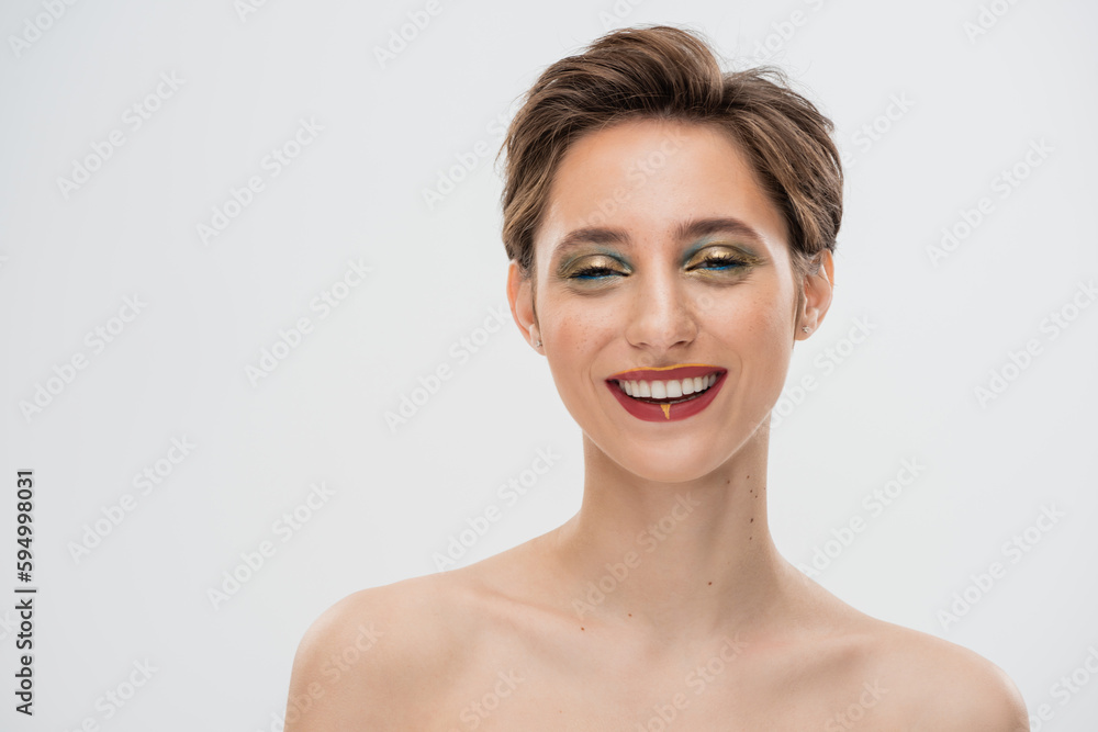 overjoyed young woman with short hair and bright makeup looking at camera isolated on grey. overjoyed young woman with short hair and bright makeup looking at camera isolated on grey.