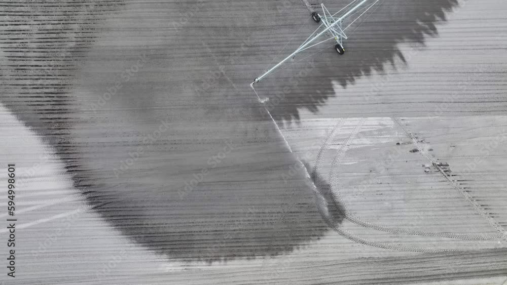 Aerial view of irrigation system watering farm field during dry season. Industrial sprinkler spraying water on farmland ground for crops growth during period of drought Aerial view of irrigation system watering farm field during dry season. Industrial sprinkler spraying water on farmland ground for crops growth during period of drought