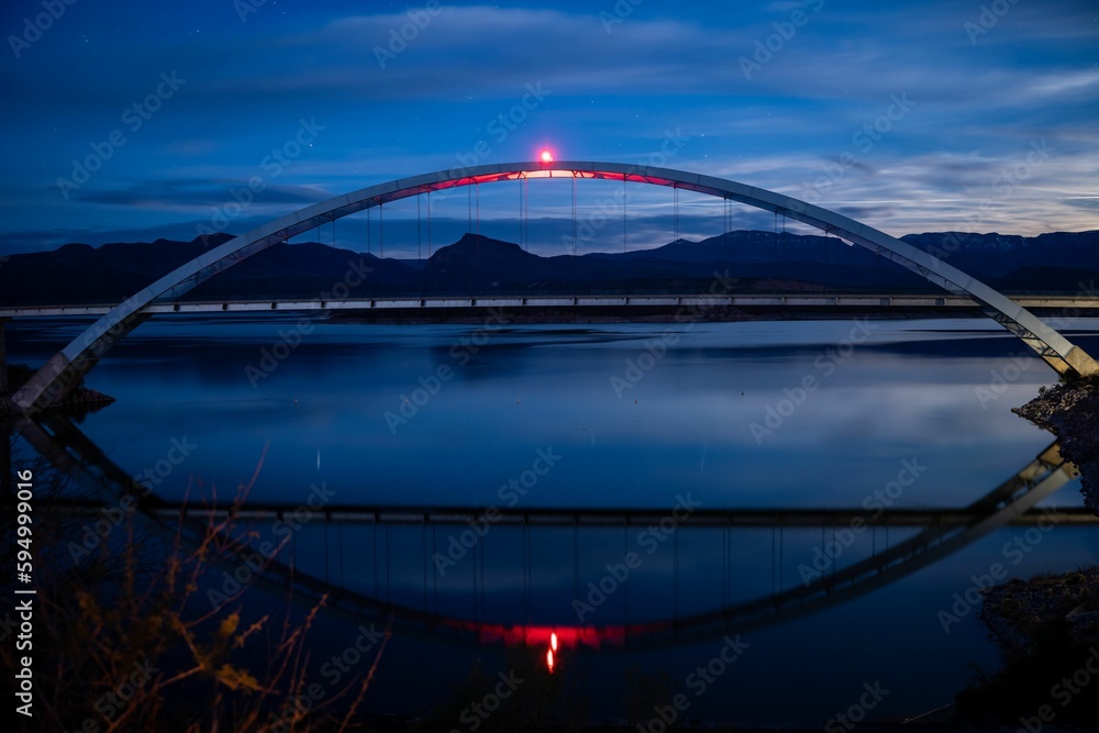 Beautiful nighttime scene of the Theodore Roosevelt Lake Bridge illuminated by a bright light Beautiful nighttime scene of the Theodore Roosevelt Lake Bridge illuminated by a bright light