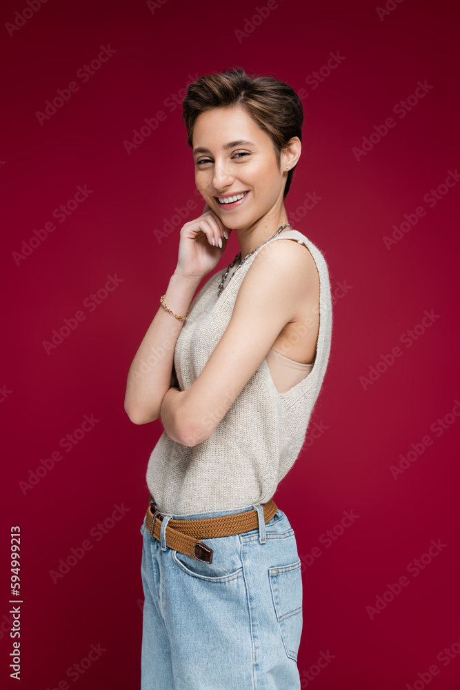 charming young woman with short hair smiling on dark red background. charming young woman with short hair smiling on dark red background.