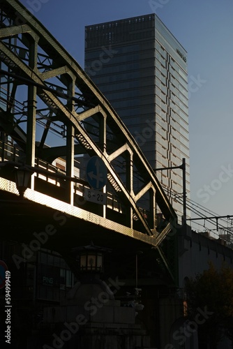 Train travelling across a bridge with a towering skyscraper providing a grand backdrop