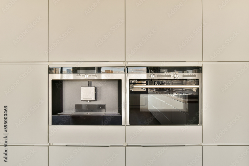 Fototapeta premium two ovens in a kitchen with white cabinets and black counter tops on either side, one has an open door