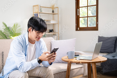 Photo of young cheerful man happy positive smile read browse internet cellphone chat type sms sit couch indoors
