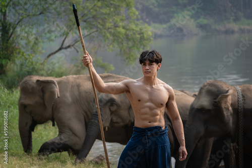 Young handsome mahout with a group of elephants takes a bath happily in the large ponds of natural forest on the mountain travel destination attraction elephant Thailand.