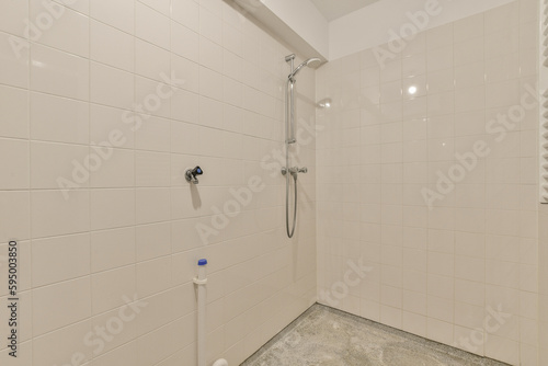 a bathroom with white tiles on the walls and shower head mounted to the wall next to the toilet in the corner