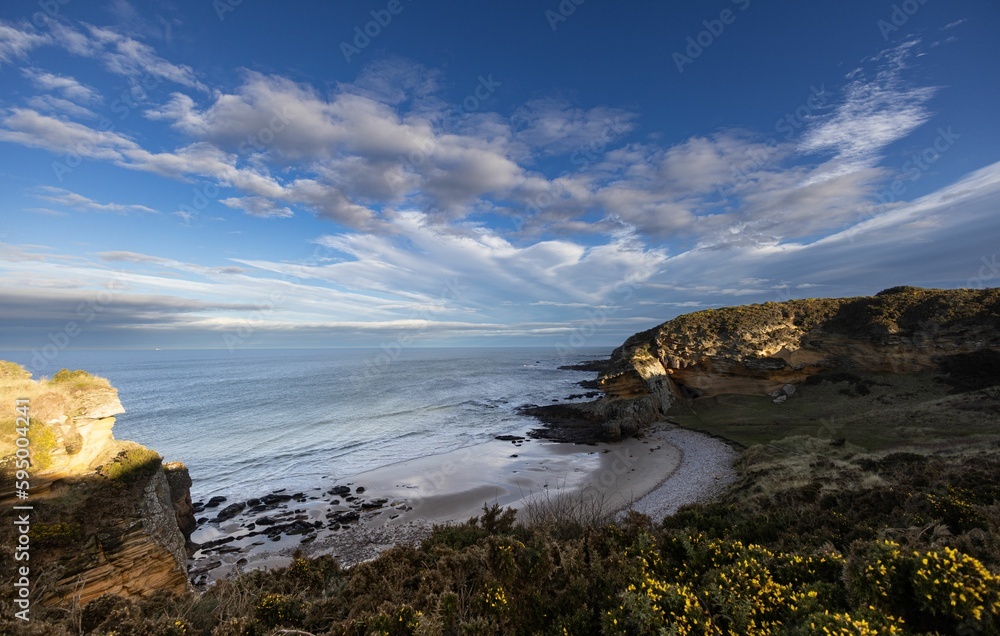 Expansive coastal landscape featuring a rocky shoreline adjacent to cliffs in the United Kingdom