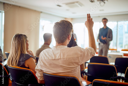 A young businessman asks a question during a business lecture in the conference room. Business, people, company