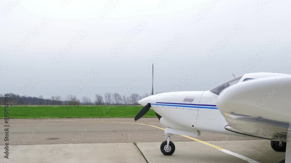 Single engine propeller airplane is standing in front of an airstrip. Transportation for tourists and locals. Small white airplane existing hangar preparing for flight. Single engine propeller airplane is standing in front of an airstrip. Transportation for tourists and locals. Small white airplane existing hangar preparing for flight.