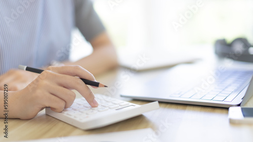 Businesswoman presses a calculator to calculate earnings and analyze company earnings in his private office, Information in finance and accounting, Company performance and revenue.