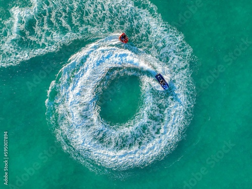 Aerial top view of a speed boat navigating the open ocean performing thrilling tricks and maneuvers