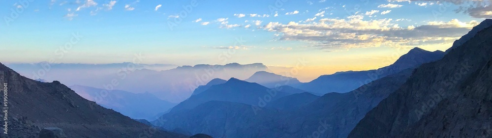 Breathtaking view of a majestic mountain range with wispy clouds in the background