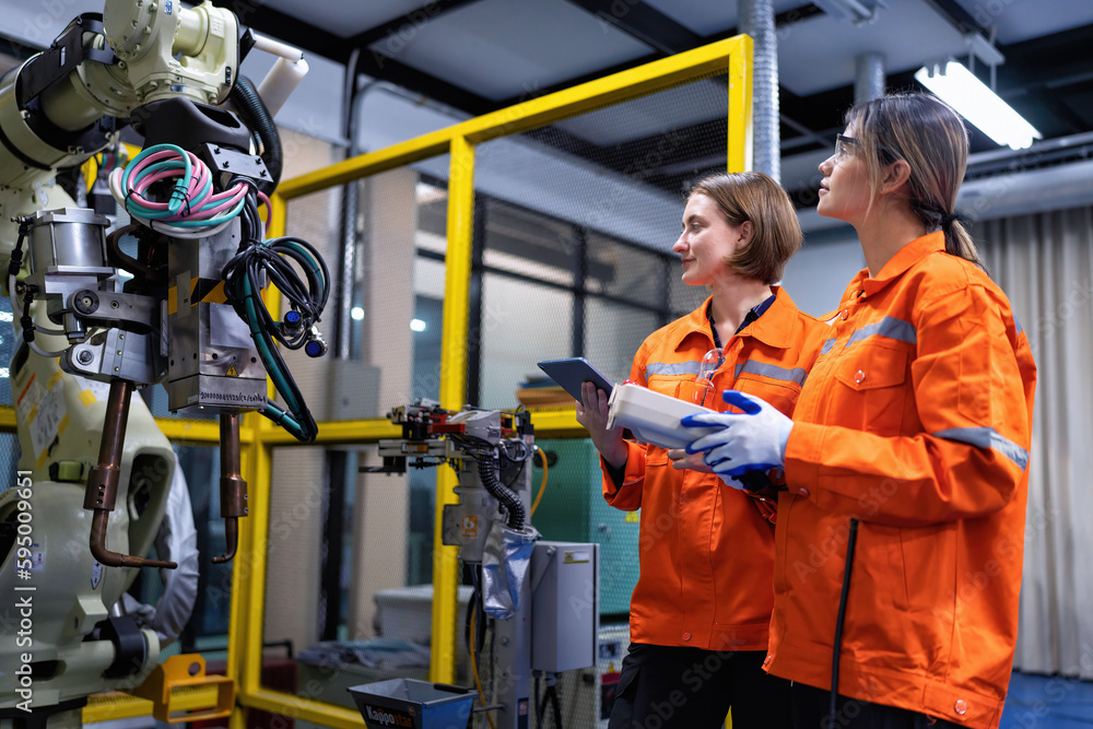 Girl engineer commissioning operating programming and looking at robot machine in the factory Girl engineer commissioning operating programming and looking at robot machine in the factory