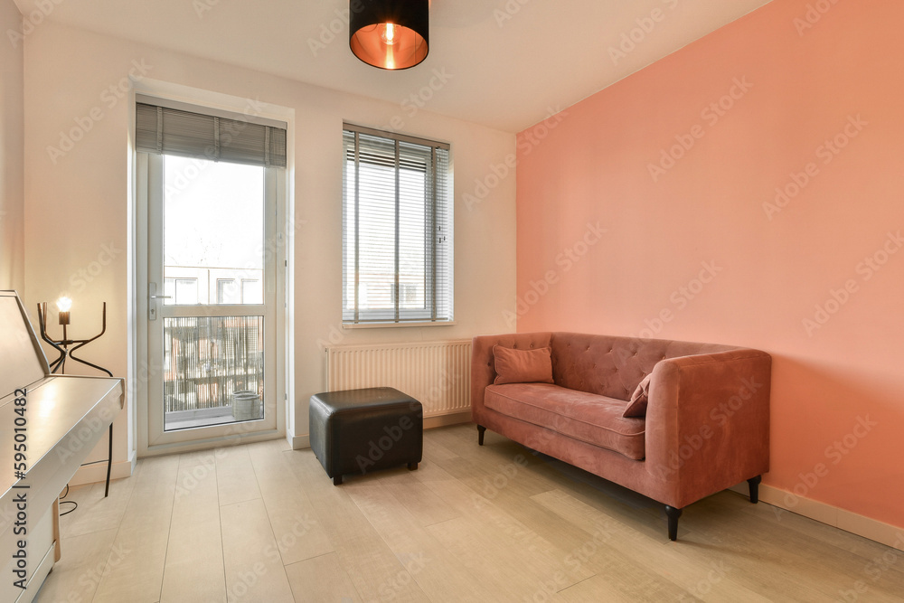Fototapeta premium a living room with pink walls and white flooring, an orange couch is in the corner of the room