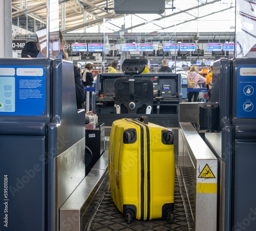 Passenger's yellow suitcase on a conveyor belt during check-in at an international airport